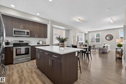 Open-concept living space featuring wood-finish flooring throughout - 61 2803 James Mowatt Trail, Edmonton, AB - Indoor Photo Showing Kitchen With Stainless Steel Kitchen With Upgraded Kitchen