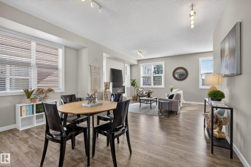 Open-concept living area featuring wood-finish flooring, abundant natural light, a built-in fireplace, recessed lighting, and neutral wall tones - 61 2803 James Mowatt Trail, Edmonton, AB - Indoor Photo Showing Dining Room