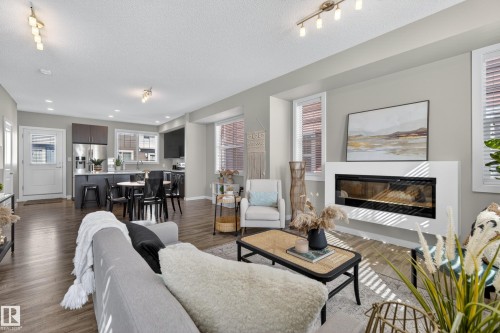 Open-concept living space featuring wood-finish flooring, a contemporary fireplace, and recessed lighting - 61 2803 James Mowatt Trail, Edmonton, AB - Indoor Photo Showing Living Room With Fireplace