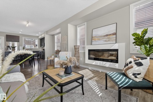 Open-concept living area featuring wood-finish flooring, an integrated linear fireplace, and recessed lighting - 61 2803 James Mowatt Trail, Edmonton, AB - Indoor Photo Showing Living Room With Fireplace