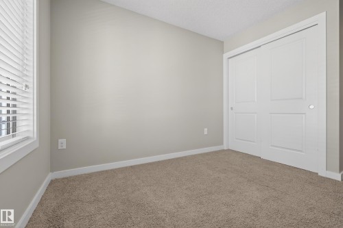 Neutral tone walls with white trim, a window with blinds, and a two-panel sliding closet door - 61 2803 James Mowatt Trail, Edmonton, AB - Indoor Photo Showing Other Room