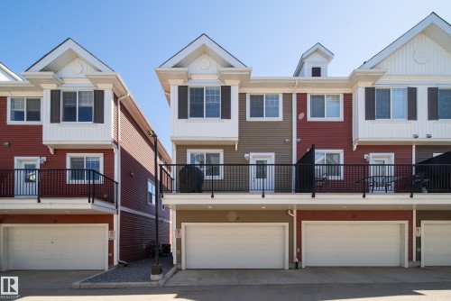 Townhouse exterior featuring a multi-level design with red and tan siding - 61 2803 James Mowatt Trail, Edmonton, AB - Outdoor With Facade
