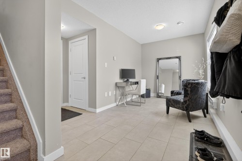 Spacious entryway featuring light-colored tile flooring, neutral wall paint, and a white interior door - 61 2803 James Mowatt Trail, Edmonton, AB - Indoor Photo Showing Other Room