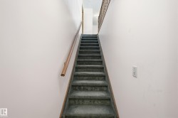 Carpeted staircase with light wood handrail - 