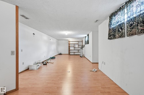 Spacious lower-level room featuring wood-finish flooring, white walls, and built-in shelving - 1242 Joyce Crescent, Edmonton, AB - Indoor Photo Showing Other Room
