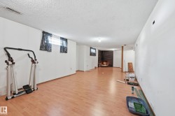 Spacious lower level featuring wood-finish flooring and a corner brick fireplace - 