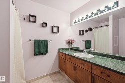 Full vanity mirror with an overhead ten-bulb light fixture, a green countertop with an integrated sink, and wood cabinetry - 