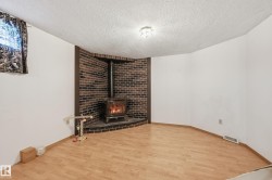 Wood-finish flooring and white walls complement a corner brick-clad wood-burning stove with a matching hearth - 