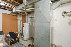 Basement utility area featuring exposed wood ceiling joists, a water heater, and extensive ductwork - 