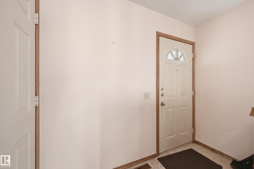 Entryway featuring a paneled door with an arched window, wood-finish trim, and light-toned wall finishes - 1242 Joyce Crescent, Edmonton, AB - Indoor Photo Showing Other Room