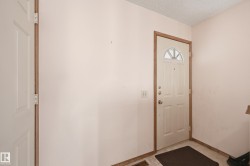 Entryway featuring a paneled door with an arched window, wood-finish trim, and light-toned wall finishes - 