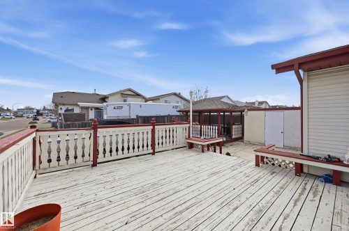 Spacious exterior deck with white wood planks and a red-trimmed railing, featuring built-in benches, an adjacent gazebo structure, and a storage shed - 1242 Joyce Crescent, Edmonton, AB - Outdoor With Exterior