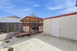 Decked outdoor space featuring a red-trimmed gazebo, stucco exterior wall, and private perimeter fencing - 