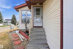 Front entry featuring concrete steps, decorative metal handrail, and a storm door - 