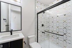 Bathroom featuring a walk-in shower with patterned tile, glass enclosure, and matte black fixtures - 