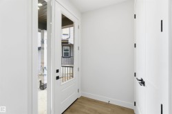Entryway featuring a white door with a clear glass insert, matte black hardware, and wood-finish flooring - 