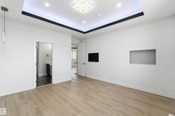 Spacious room featuring light wood-finish flooring and a tray ceiling with recessed lighting - 
