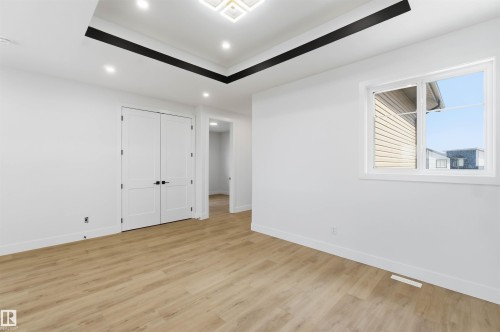 Spacious room featuring wood-finish flooring, white walls, and a tray ceiling with recessed lighting - 417 Pine Point(E), Leduc, AB - Indoor Photo Showing Other Room