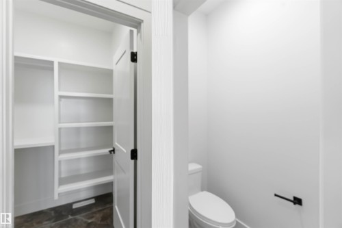 White built-in shelving with multiple levels, featuring a dark floor, and a white interior door with black hardware - 417 Pine Point(E), Leduc, AB - Indoor Photo Showing Bathroom