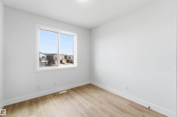 Bright room featuring light wood-finish flooring and crisp white walls - 