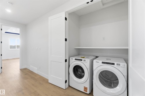 Dedicated laundry closet featuring a built-in shelf, white walls, and wood-finish flooring - 417 Pine Point(E), Leduc, AB - Indoor Photo Showing Laundry Room