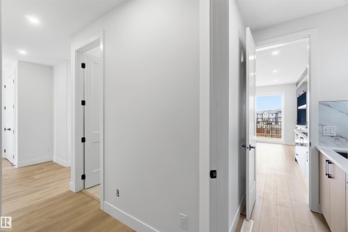 Hallway featuring wood-finish flooring, recessed lighting, white trim, and matte black door hardware - 417 Pine Point(E), Leduc, AB - Indoor
