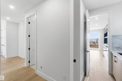 Hallway featuring wood-finish flooring, recessed lighting, white trim, and matte black door hardware - 