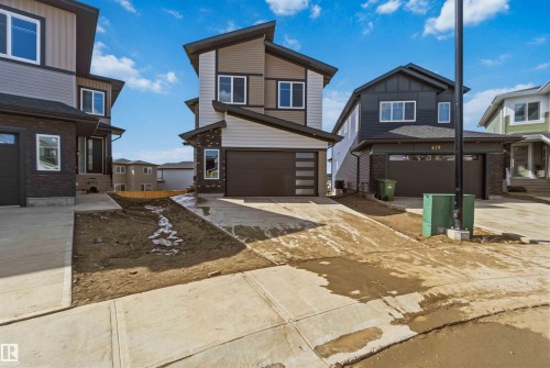 Modern-style exterior featuring a peaked roofline, multi-tone siding, an attached garage with horizontal frosted-glass panels, and white-framed windows - 417 Pine Point(E), Leduc, AB - Outdoor