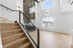Bright interior featuring a grand staircase with wood treads and a glass railing - 