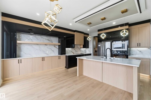 Gourmet kitchen featuring light wood-finish flooring, a central island with a white countertop and built-in sink, and custom light wood cabinetry - 417 Pine Point(E), Leduc, AB - Indoor Photo Showing Kitchen With Upgraded Kitchen