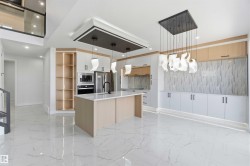 Spacious kitchen featuring an expansive island with a quartz countertop, integrated stainless steel appliances, and custom cabinetry - 
