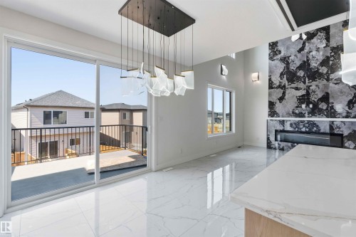 Spacious living area featuring polished tile flooring, a statement chandelier, and a black and white tiled accent wall with an integrated linear fireplace - 415 Pine Point(E), Leduc, AB -  With Exterior