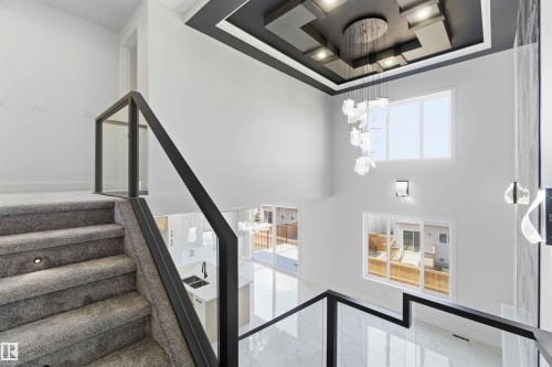 Two-story open concept foyer featuring a contemporary chandelier, recessed ceiling lighting, and a floating glass and metal railing system - 415 Pine Point(E), Leduc, AB - Indoor Photo Showing Other Room