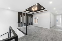 Open loft area featuring a tray ceiling with recessed lighting, a modern chandelier, and patterned accent wall - 