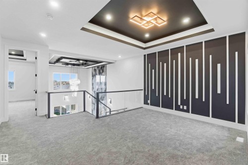 Upper-level landing featuring a decorative accent wall with vertical white trim, a coffered ceiling with recessed lighting and a contemporary central fixture, and gray carpet flooring - 415 Pine Point(E), Leduc, AB - Indoor Photo Showing Other Room