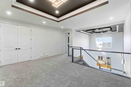 Open landing area featuring gray carpeting, modern glass and metal railing, and recessed ceiling lighting - 415 Pine Point(E), Leduc, AB - Indoor Photo Showing Other Room