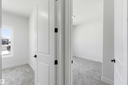 Two rooms featuring light gray carpeting, crisp white walls, and modern white paneled doors with matte black hardware - 