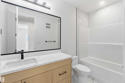 Bathroom featuring a wood-finish vanity with an integrated sink, quartz countertop, and matte black faucet - 415 Pine Point(E), Leduc, AB - Indoor Photo Showing Bathroom