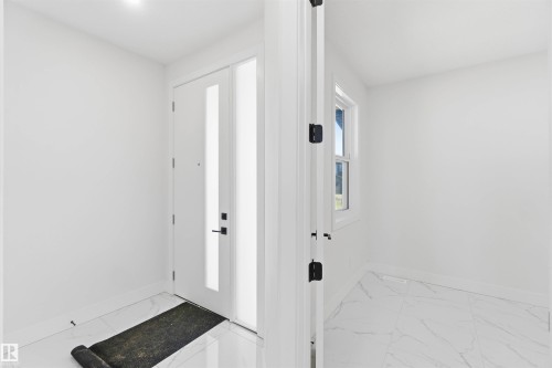 Entryway featuring a white door with vertical frosted glass panels, matte black hardware, and a coordinating frosted glass sidelight - 415 Pine Point(E), Leduc, AB - Indoor Photo Showing Other Room