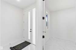 Entryway featuring a white door with vertical frosted glass panels, matte black hardware, and a coordinating frosted glass sidelight - 