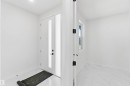 Entryway featuring a white door with vertical frosted glass panels, matte black hardware, and a coordinating frosted glass sidelight - 415 Pine Point(E), Leduc, AB  - Indoor Photo Showing Other Room 