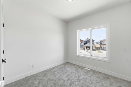 Bright interior space featuring a large window, light gray carpeting, crisp white walls, white trim, and a modern ceiling light fixture - 415 Pine Point(E), Leduc, AB - Indoor Photo Showing Other Room