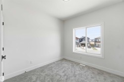 Bright interior space featuring a large window, light gray carpeting, crisp white walls, white trim, and a modern ceiling light fixture - 