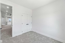 Bright room with light gray carpeting, white walls, and a double-door closet featuring matte black hardware - 