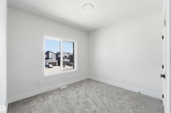 Bright interior space featuring a double-pane window, light gray carpet, white baseboards, and a circular flush-mount ceiling light - 