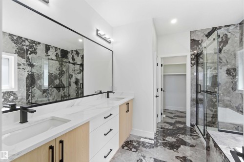 Modern bathroom featuring a dual vanity with white countertops, light wood-finish cabinetry, and matte black fixtures - 415 Pine Point(E), Leduc, AB - Indoor Photo Showing Bathroom