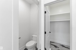 Powder room featuring a white toilet with black floor tiling - 