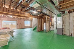 Unfinished lower level with exposed ceiling joists and ductwork, featuring a walk-out glass sliding door, two windows, and a staircase - 