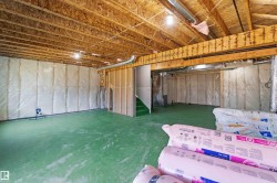 Unfinished basement featuring exposed wood joists and subflooring, insulated perimeter walls, and a green painted concrete floor - 