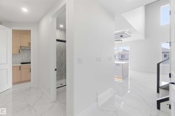 Spacious interior featuring white walls and large format marble-look tile flooring - 